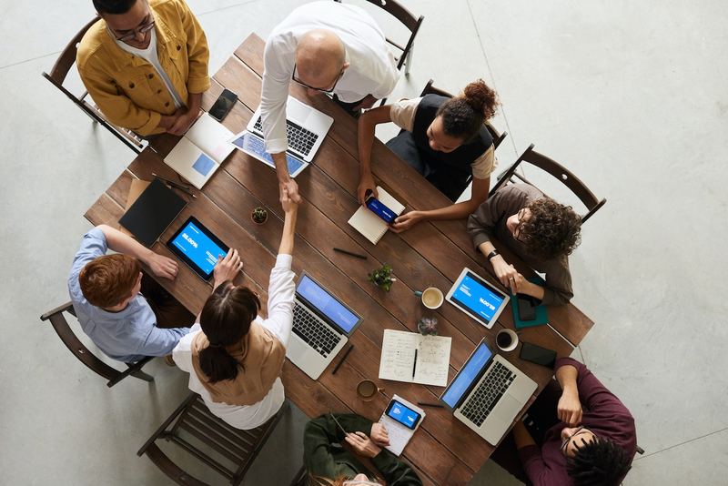 A team meeting around a table with laptops